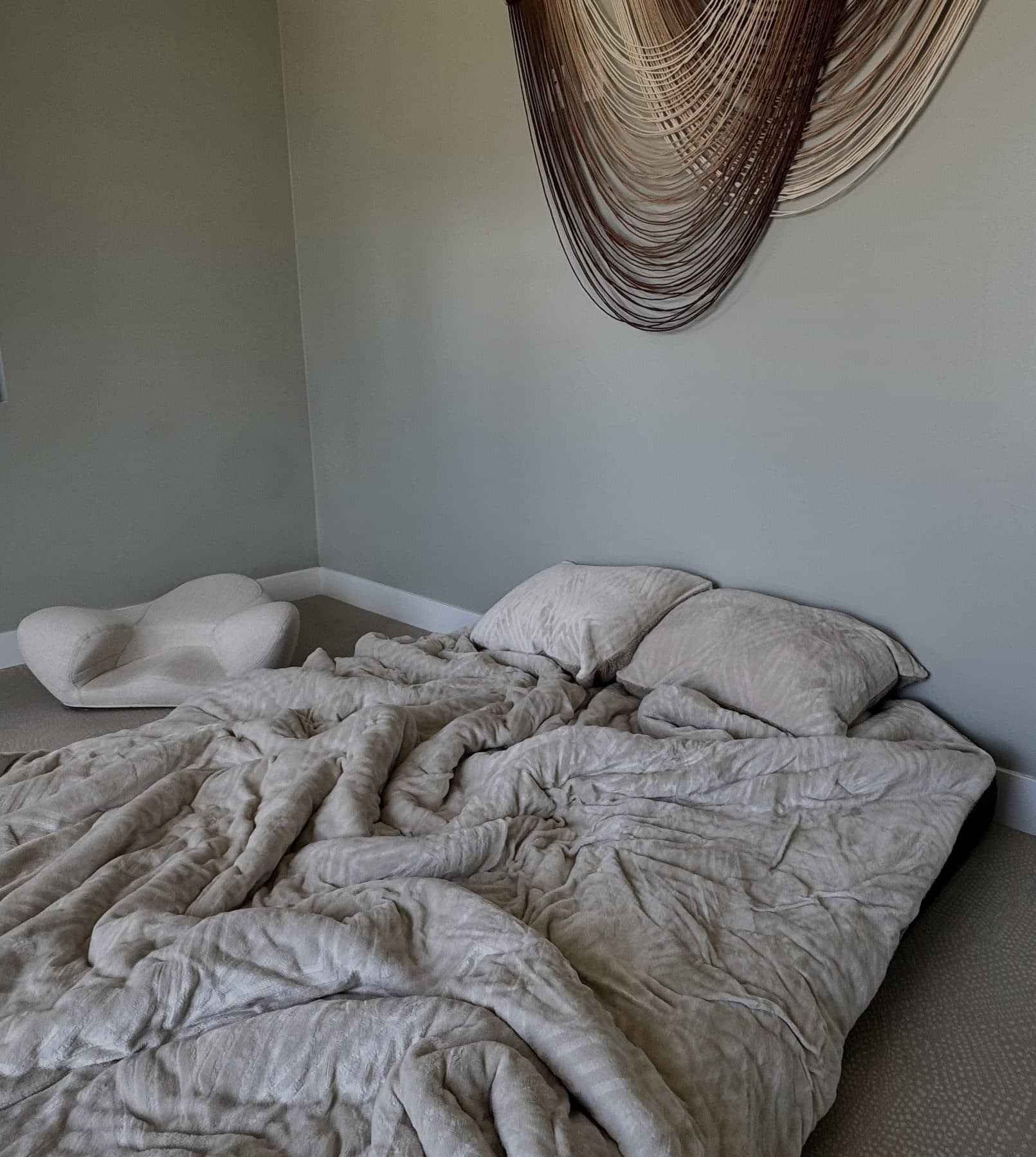 Session room bed setup with hand-woven wall hanging